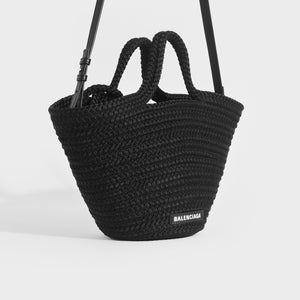 Side view of Balenciaga Ibiza nylon leather basket bag in black with crossbody strap pulled up.