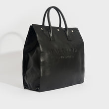 Load image into Gallery viewer, Side view of the SAINT LAURENT Rive Gauche Tote Bag in Black Leather