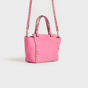 Side view of the VALENTINO Garavani Mini Rockstud Leather Tote Bag in Dawn Pink