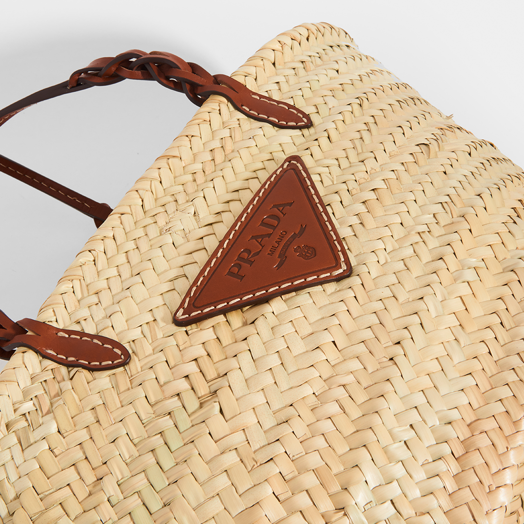 Logo view of Prada natural fibre and brown leather detailing basket bag.