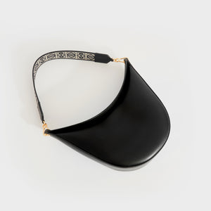 Flat shot of of Loewe Luna shoulder bag in black leather and gold hardware with canvas logo print shoulder strip