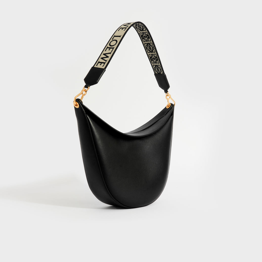 Angled view of Loewe Luna shoulder bag in black leather with logo canvas strap