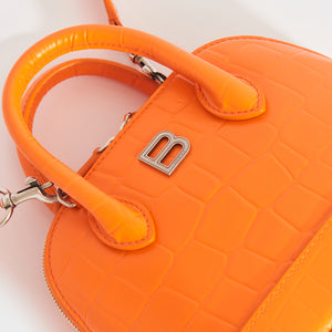 View of Balenciaga logo hardware on Balenciaga XXS Ville embossed leather tote in orange