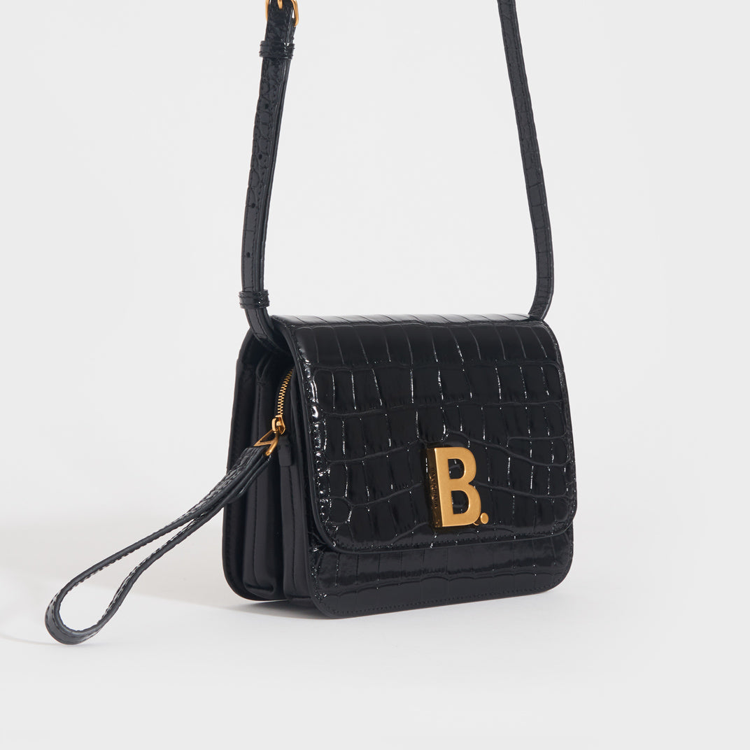 Side view of the BALENCIAGA B Small Embossed Crossbody Bag in Black