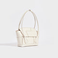 Side view of the BOTTEGA VENETA Arco Small Intrecciato Leather Tote Bag in White