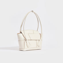 Load image into Gallery viewer, Side view of the BOTTEGA VENETA Arco Small Intrecciato Leather Tote Bag in White