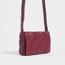 Load image into Gallery viewer, Side view of the BOTTEGA VENETA Cassette Maxi Intrecciato Bag in Bordeaux