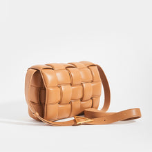 Load image into Gallery viewer, Side view of BOTTEGA VENETA Padded Cassette Crossbody Bag in Caramel Lambskin Leather