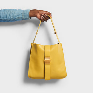 Model holding the the BOTTEGA VENETA The Marie Shoulder Bag in Yellow