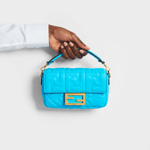 Model holding the FENDI Mini Baguette Bag in Turquoise Embossed Leather