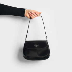Hand holding the PRADA Cleo Brushed Leather Shoulder Bag With Flap in Black