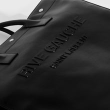 Load image into Gallery viewer, Close up of 3D logo on Saint Laurent Rive Gauche tote bag in black leather with silver hardware