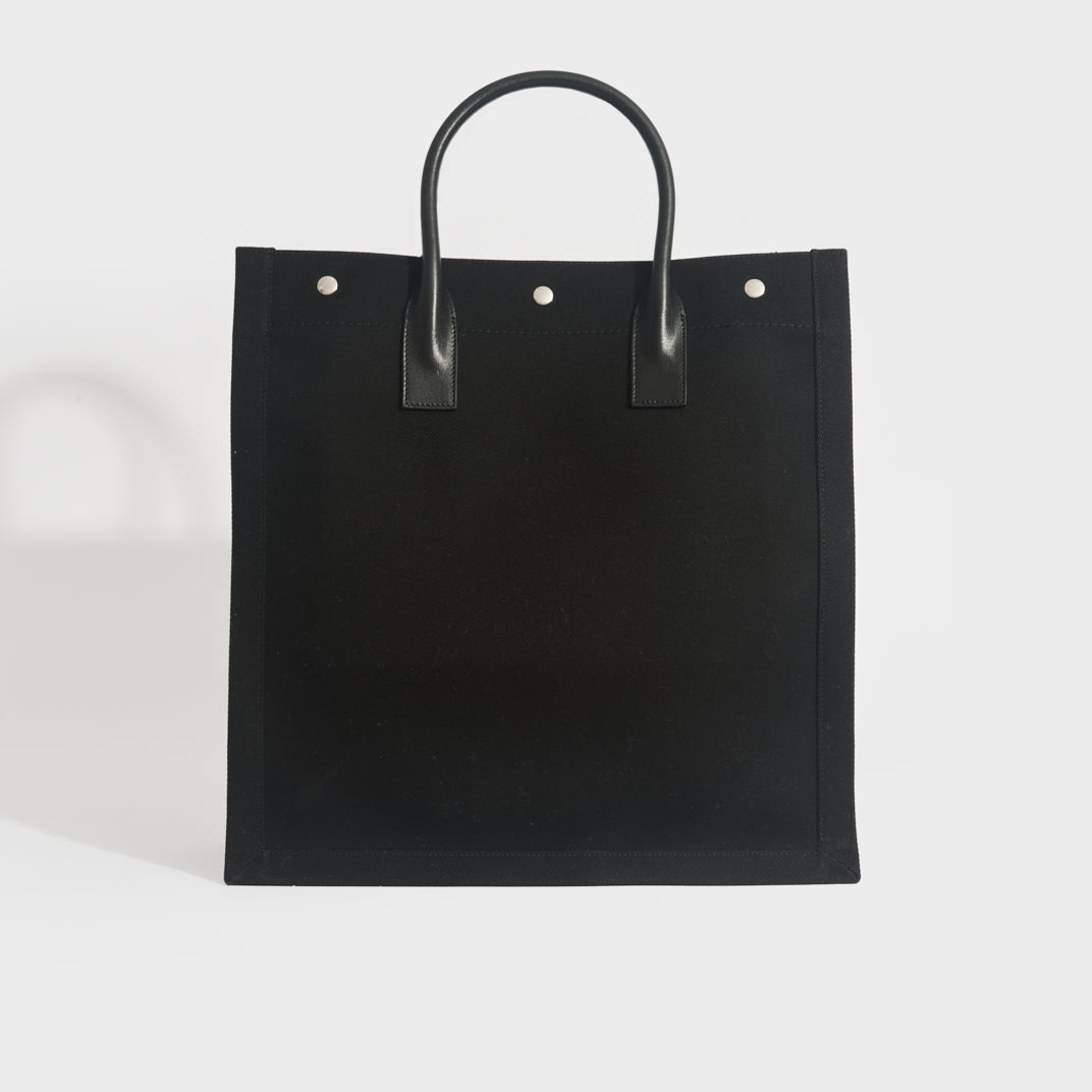 Back view of Saint Laurent Rive Gauche tote back in black canvas and black leather handles
