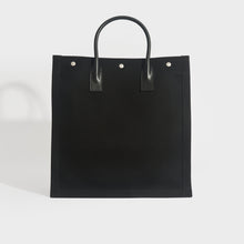 Load image into Gallery viewer, Back view of Saint Laurent Rive Gauche tote back in black canvas and black leather handles