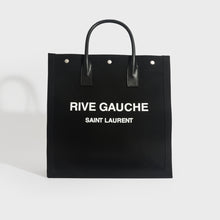 Load image into Gallery viewer, Front view of Saint Laurent Rive Gauche tote in black and canvas and white printed logo with black leather handles.