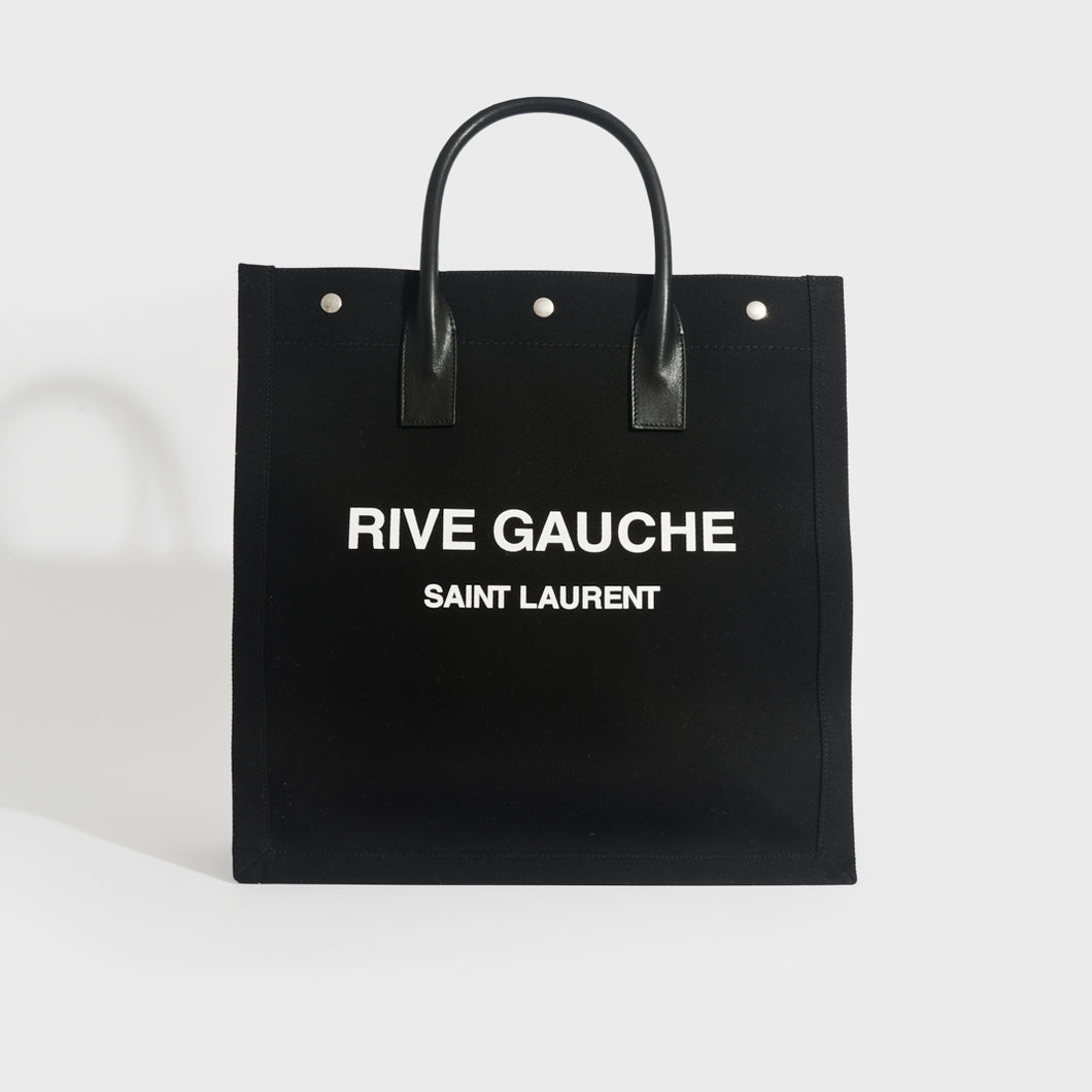 Front view of Saint Laurent Rive Gauche tote in black and canvas and white printed logo with black leather handles.