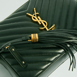Close up detail of gold YSL hardware and leather tassel on the SAINT LAURENT Lou Camera Bag in Dark Green Matelassé Leather