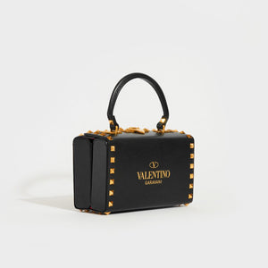 Side view of the VALENTINO Garavani Box Rockstud Alcove Leather Top Handle Bag in Black