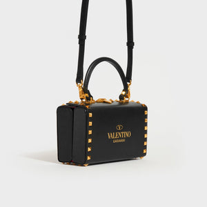 Side view of the VALENTINO Garavani Box Rockstud Alcove Leather Top Handle Bag in Black