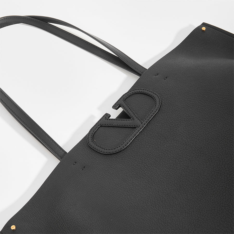 Detail of V logo on VALENTINO Garavani Fill Me Tote in Black Leather