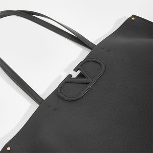 Detail of V logo on VALENTINO Garavani Fill Me Tote in Black Leather