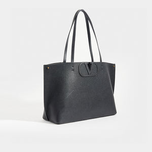 Side view of VALENTINO Garavani Fill Me Tote in Black Leather